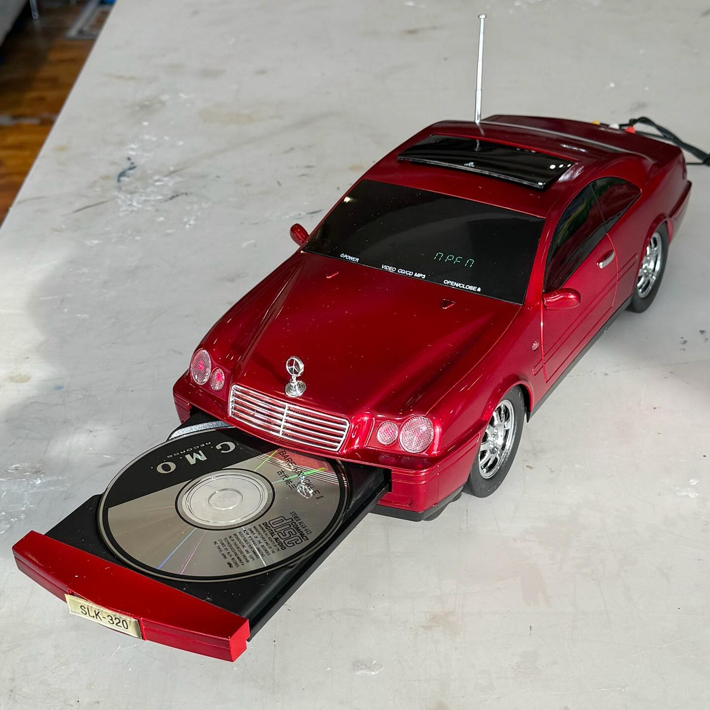 Novelty CD player built into the body of a red Mercedes coupe, disc tray sliding out the front