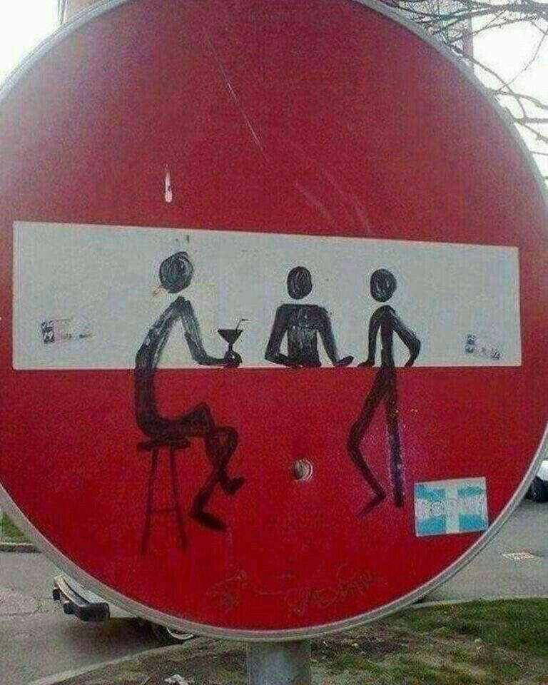 A 'no entry' road sign street-painted so the white bar becomes figures at a bar counter